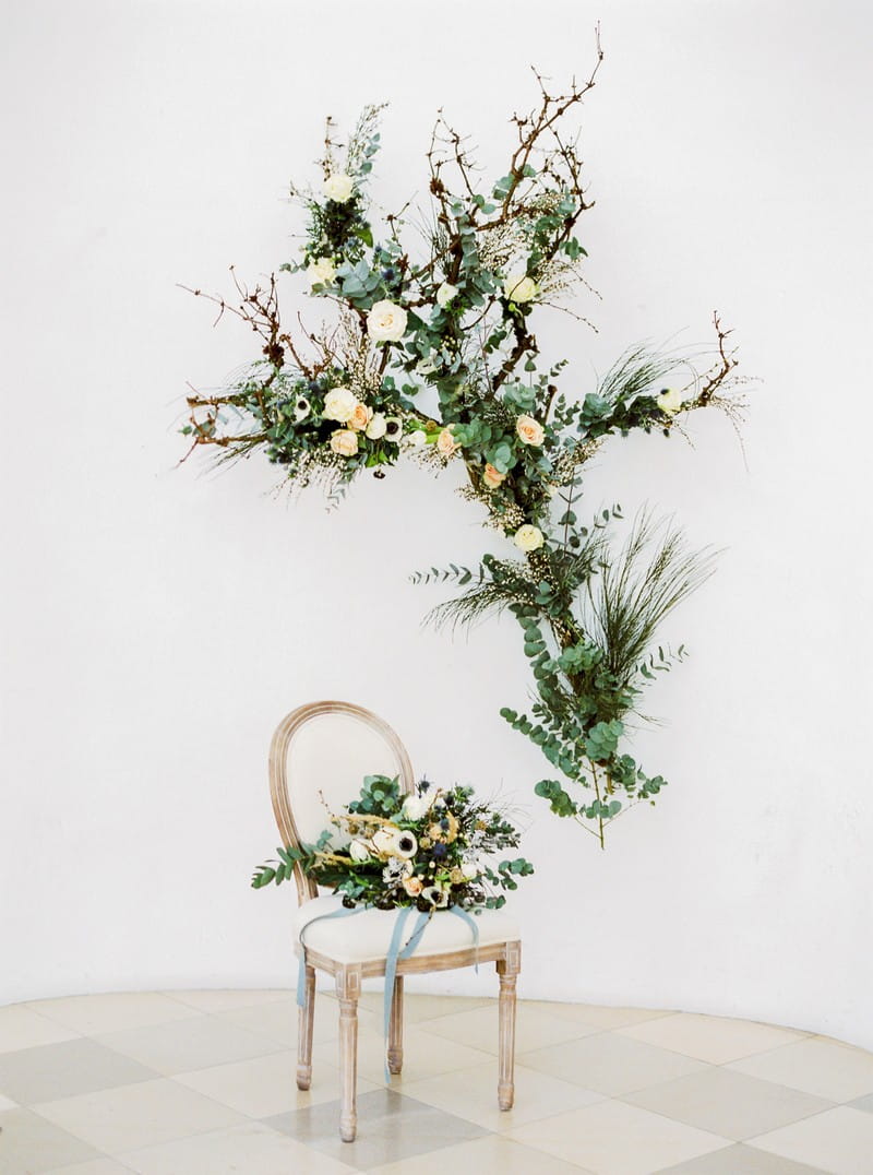 Wedding floral display on wall with bouquet on chair