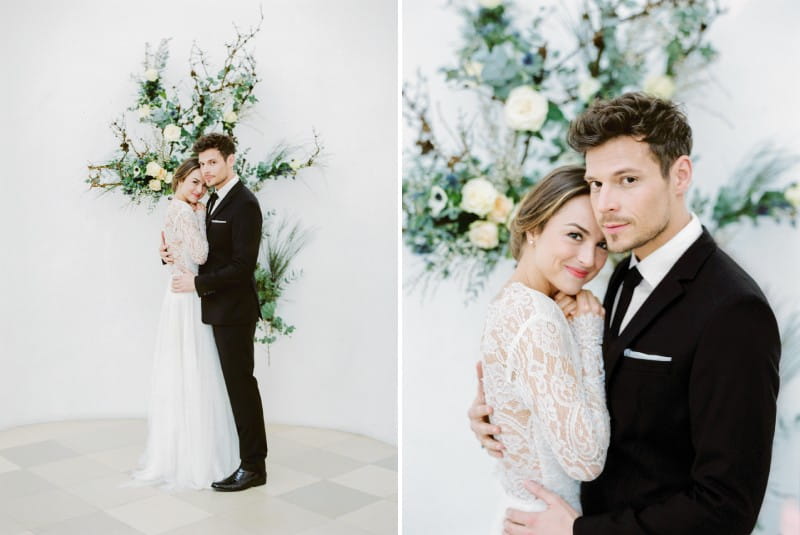 Bride and groom in front of wall floral display