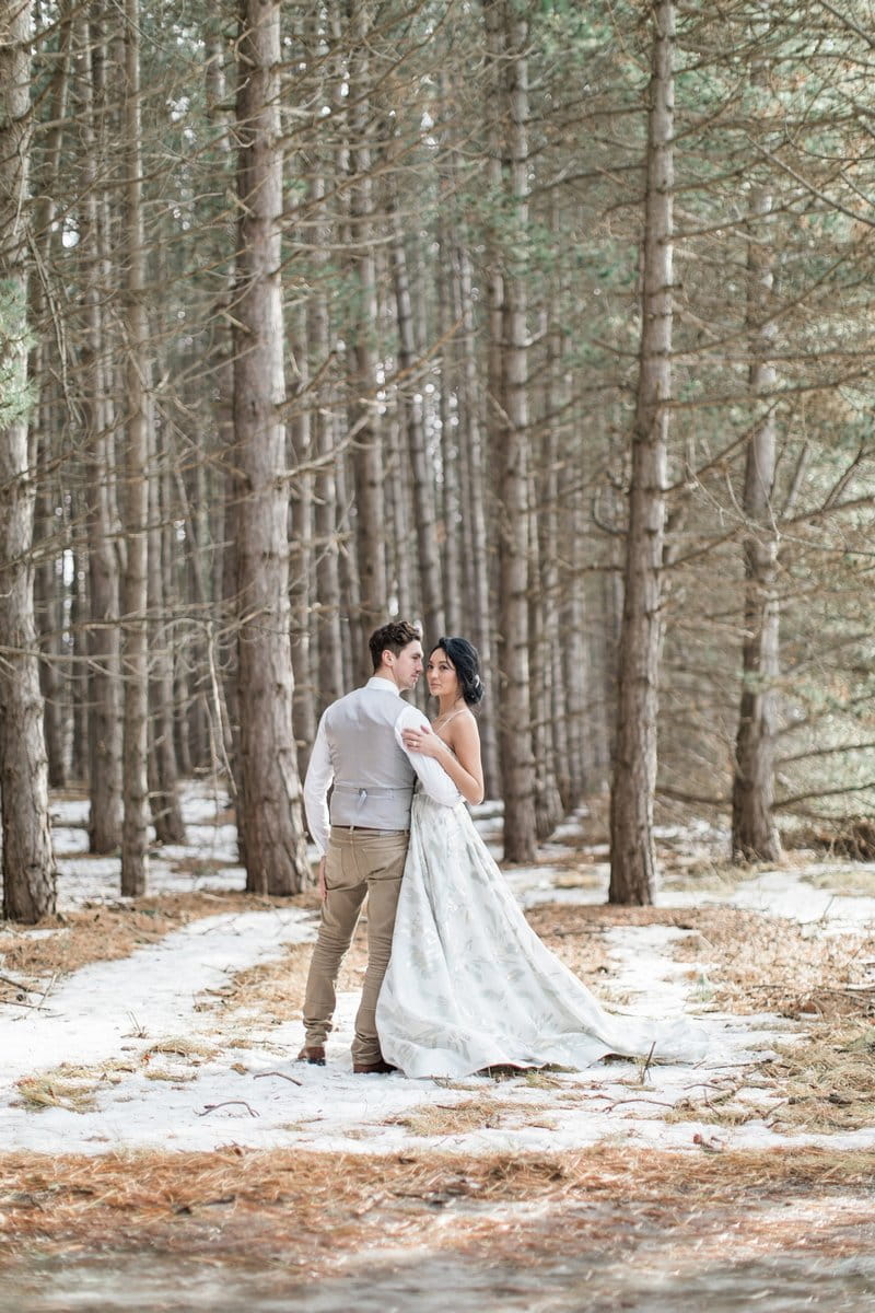 Bride and groom by trees in snow