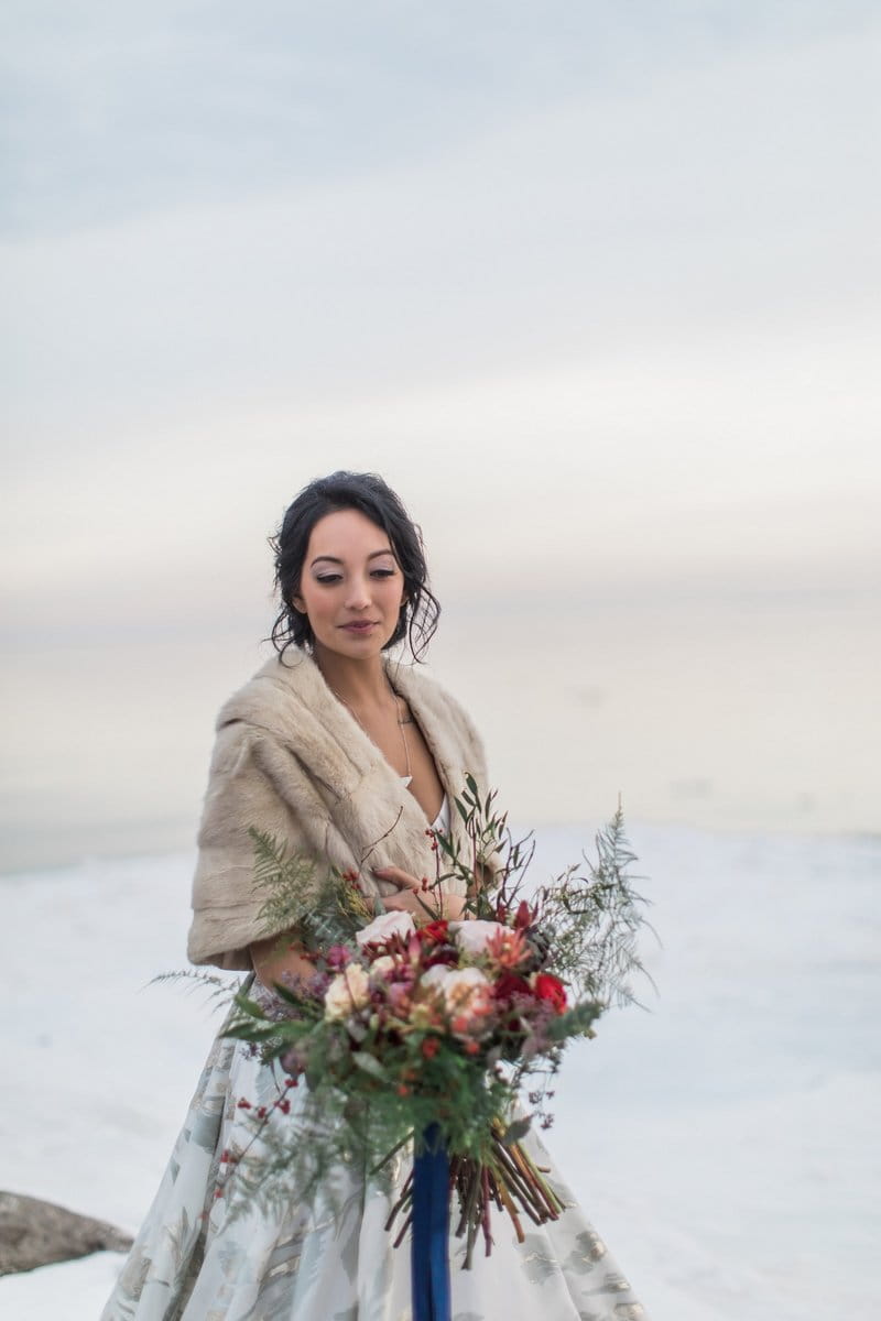 Bride wearing fur shrug holding bouquet