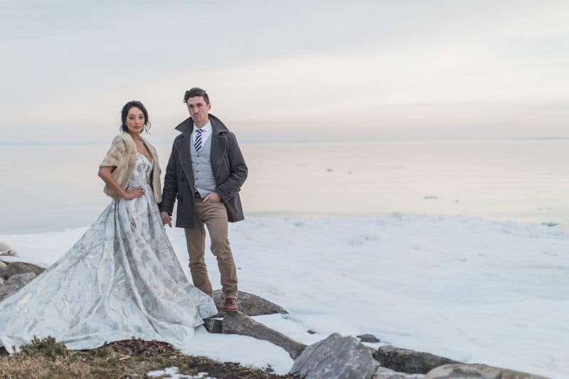 Bride and groom standing on rocks in the snow