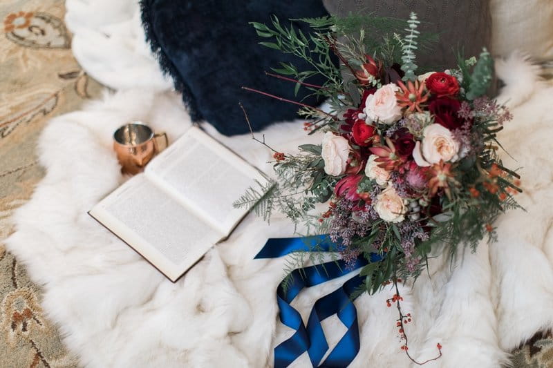 Winter wedding bouquet and book on fur blanket