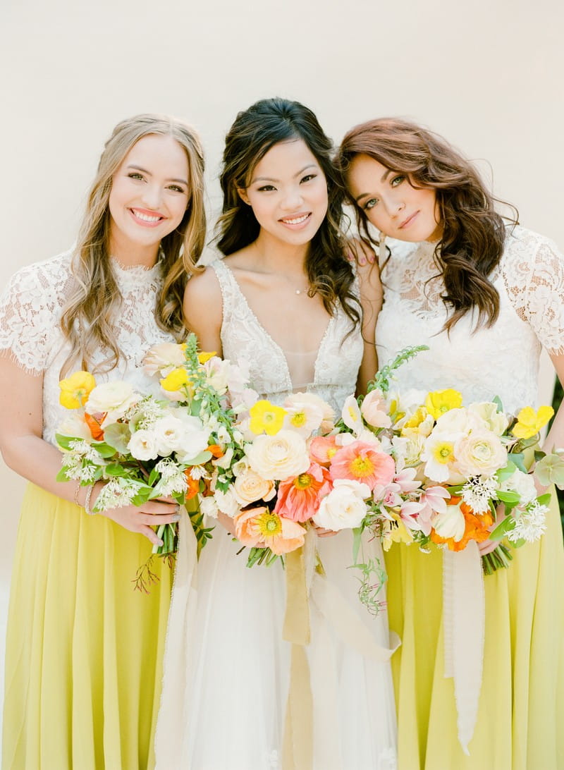 Bride with bridesmaids in yellow skirts holding colourful bouquets