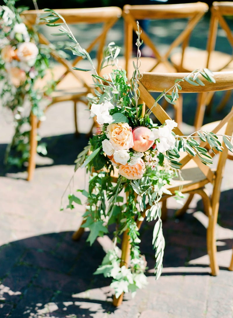 Foliage and peach flowers tied to wedding chair