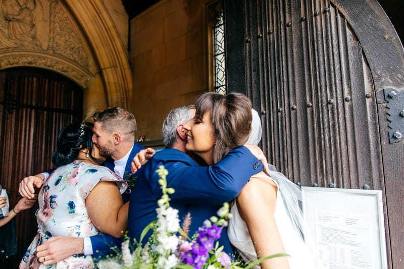 Bride and groom hugging wedding guests outside church