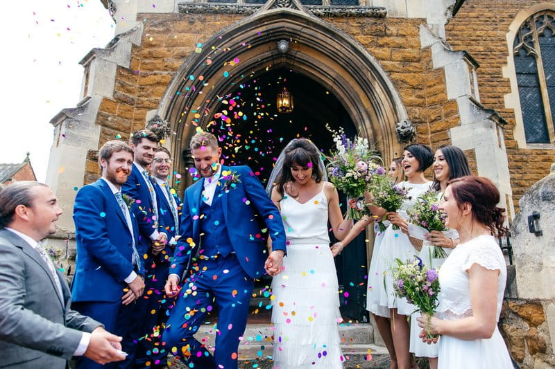 Bride and groom being showered in confetti as they walk down steps of church