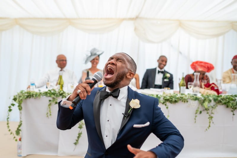 Man singing passionately in front of top table at wedding - Picture by Moritz Schmittat Photography