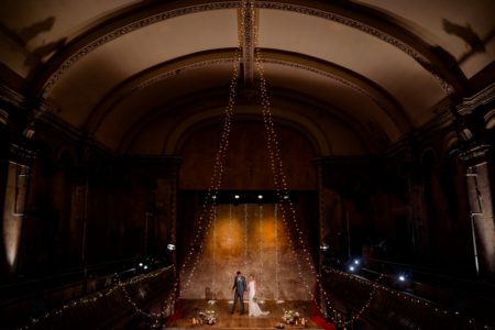 Bride and groom on stage Wiltons Music Hall wedding venue - Picture by Voyteck Photography