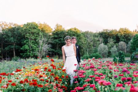 Bride and groom walking through colourful flowers - Picture by Anette Bruzan Photography