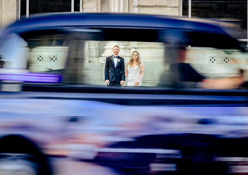 Bride and groom seen through window of blurred car driving past - Picture by Mick Cookson Photography
