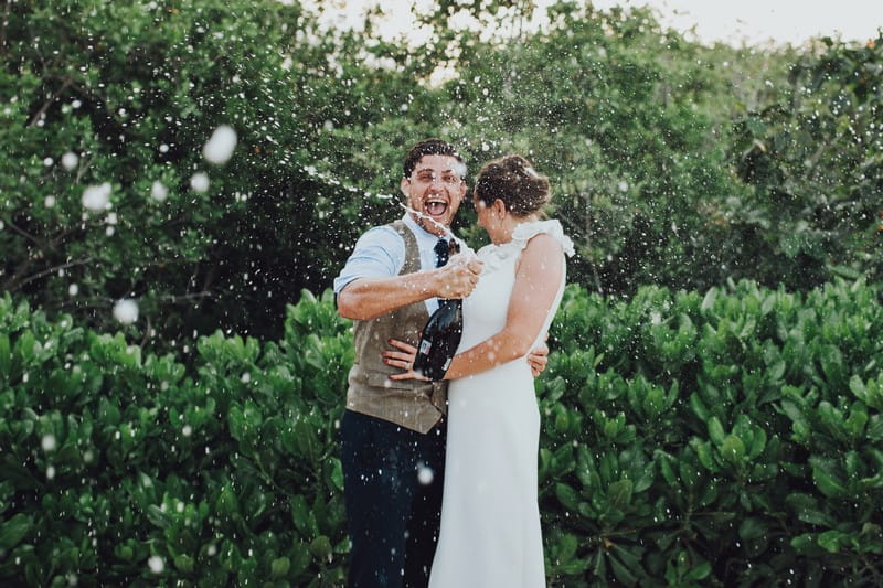 Groom spraying Champagne everywhere as bride turns away - Picture by Honeydew Moments