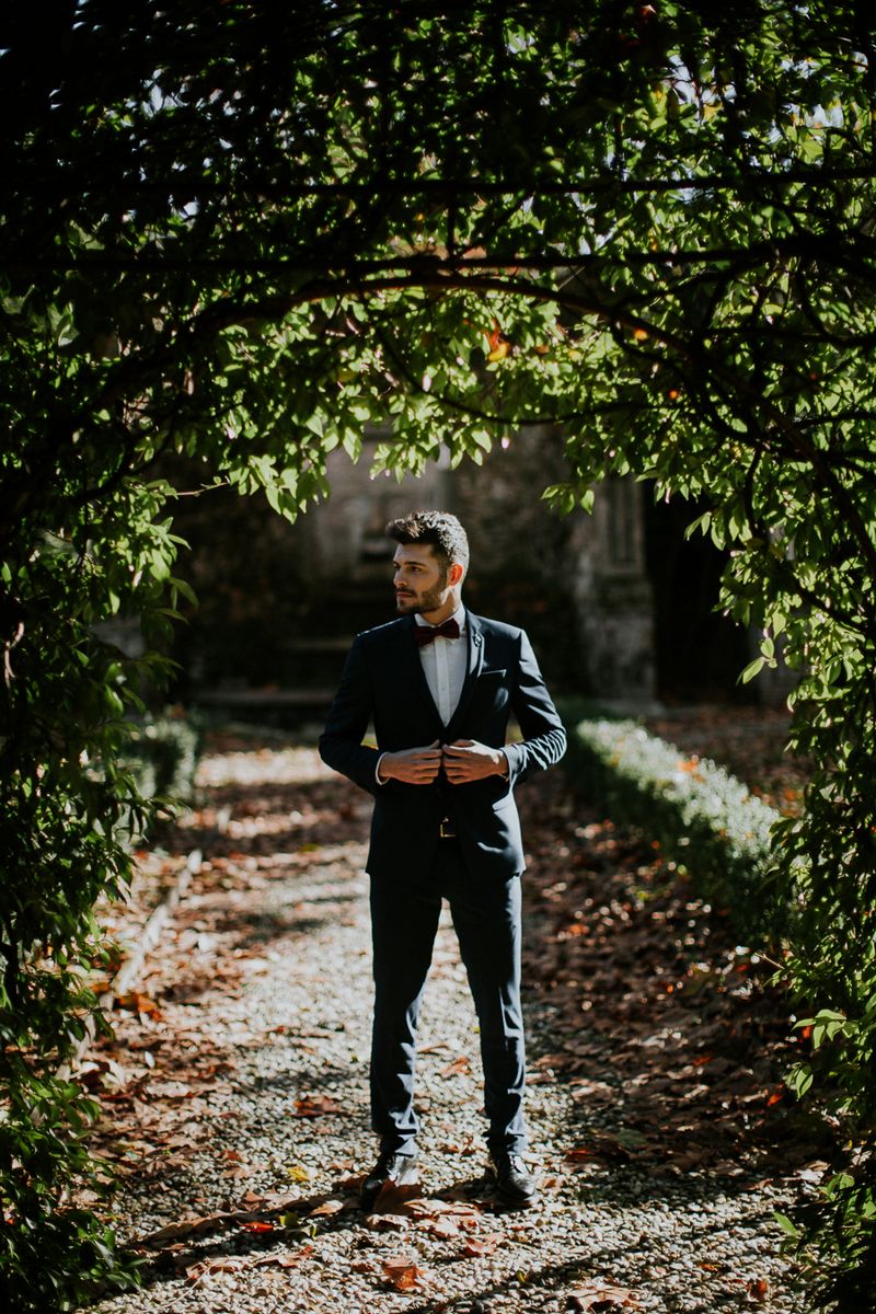 Groom standing under tree in Tuscany