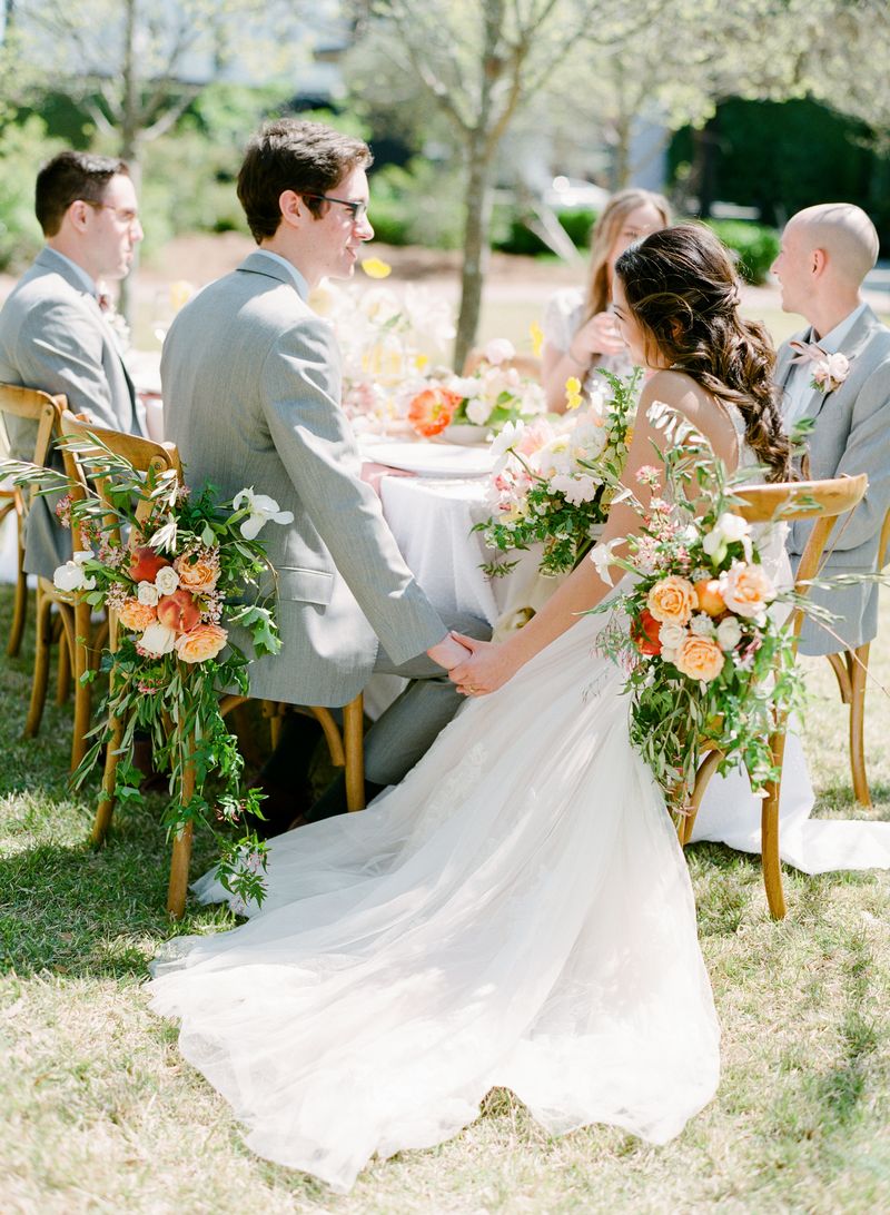 Bride and groom sitting on wedding chairs with flowers