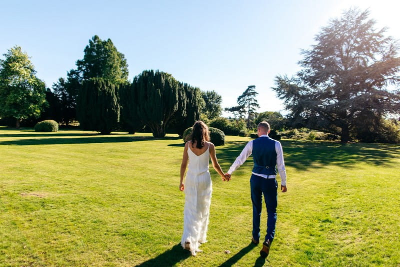 Bride and groom walking in grounds of Barton Hall