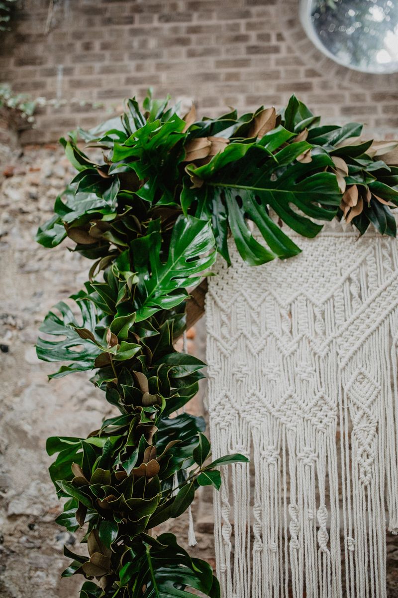 Tropical palm leaves around macramé wedding backdrop