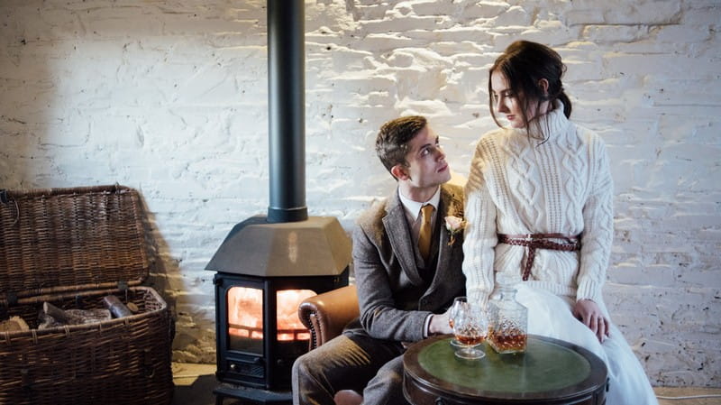 Bride and groom sitting by log burner in Coombe Trenchard