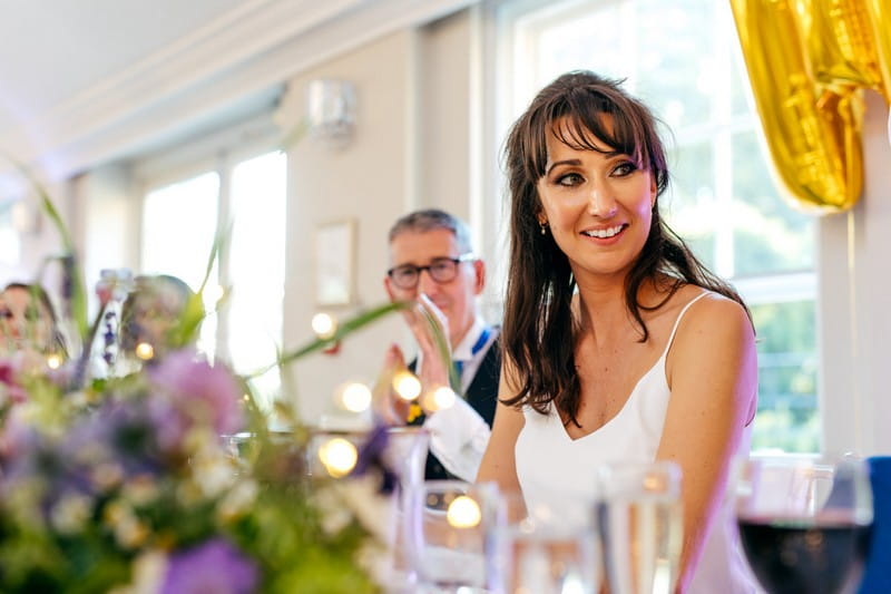 Bride looking at groom as he gives wedding speech