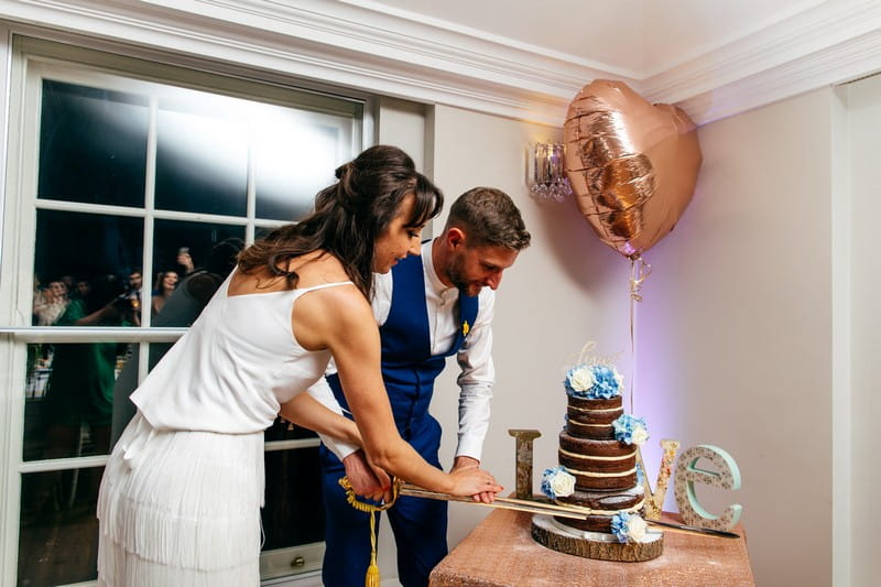 Bride and groom cutting wedding cake with sword