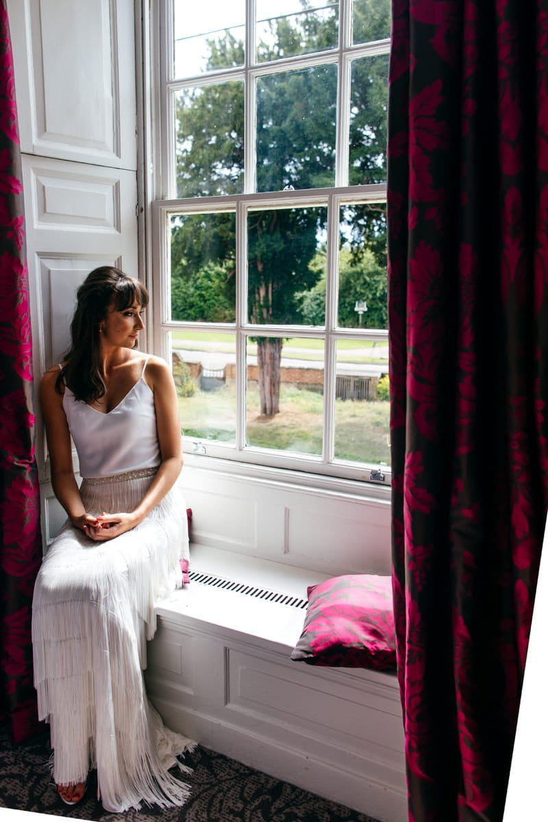 Bride sitting on window ledge at Barton Hall