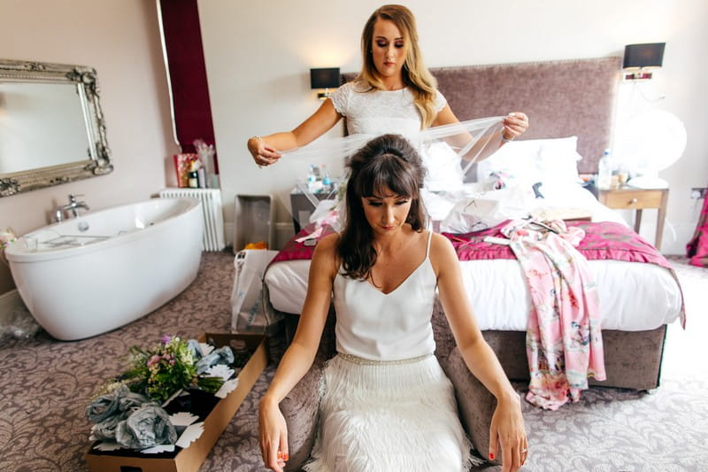 Bridesmaid helping bride put veil on