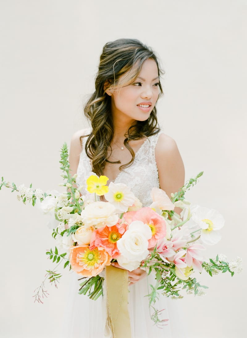 Bride holding colourful wedding bouquet with yellow and peach flowers