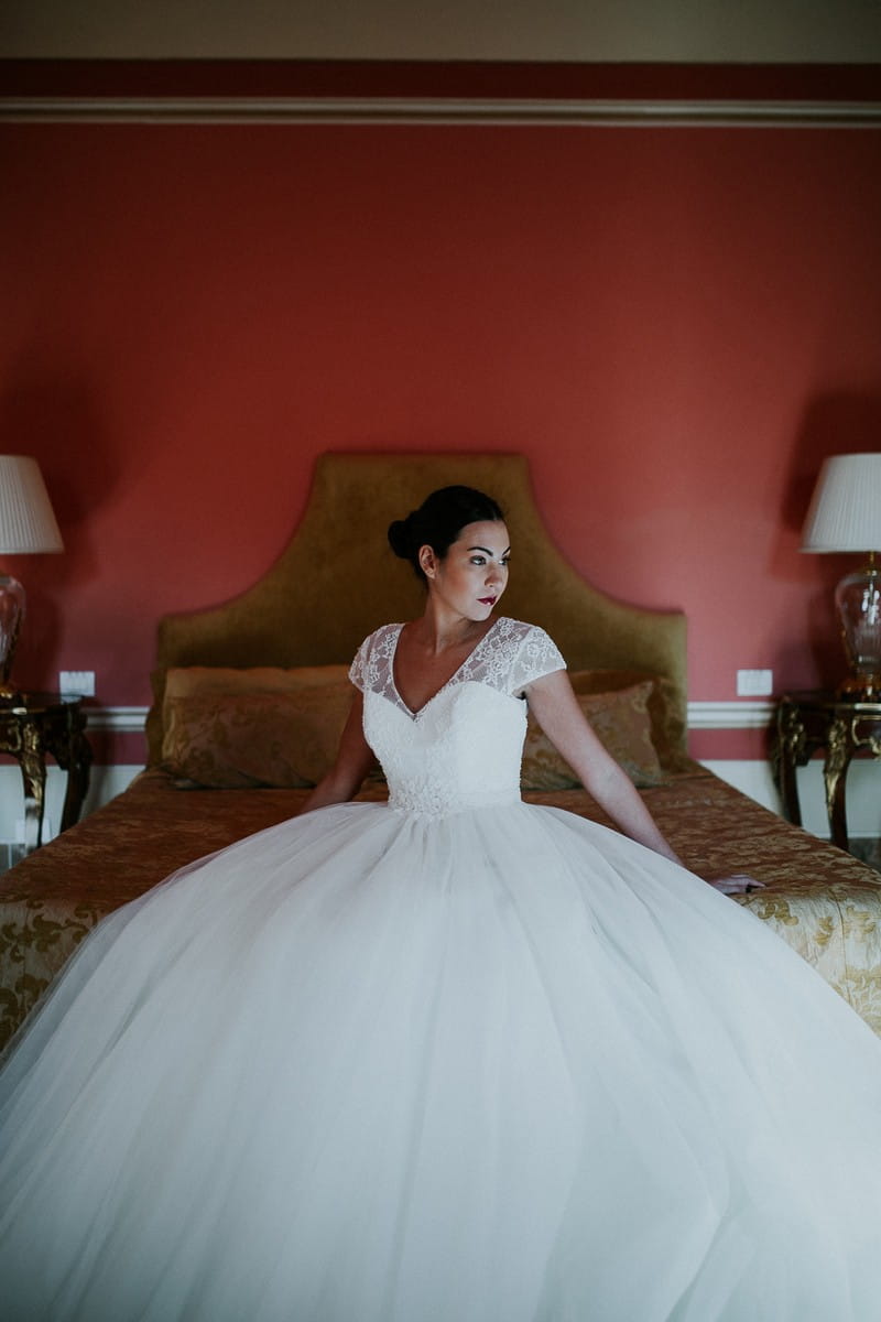 Bride sitting on bed in Villa Lenka, Tuscany