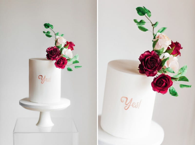 White engagement cake with 'yes' lettering and rose topper