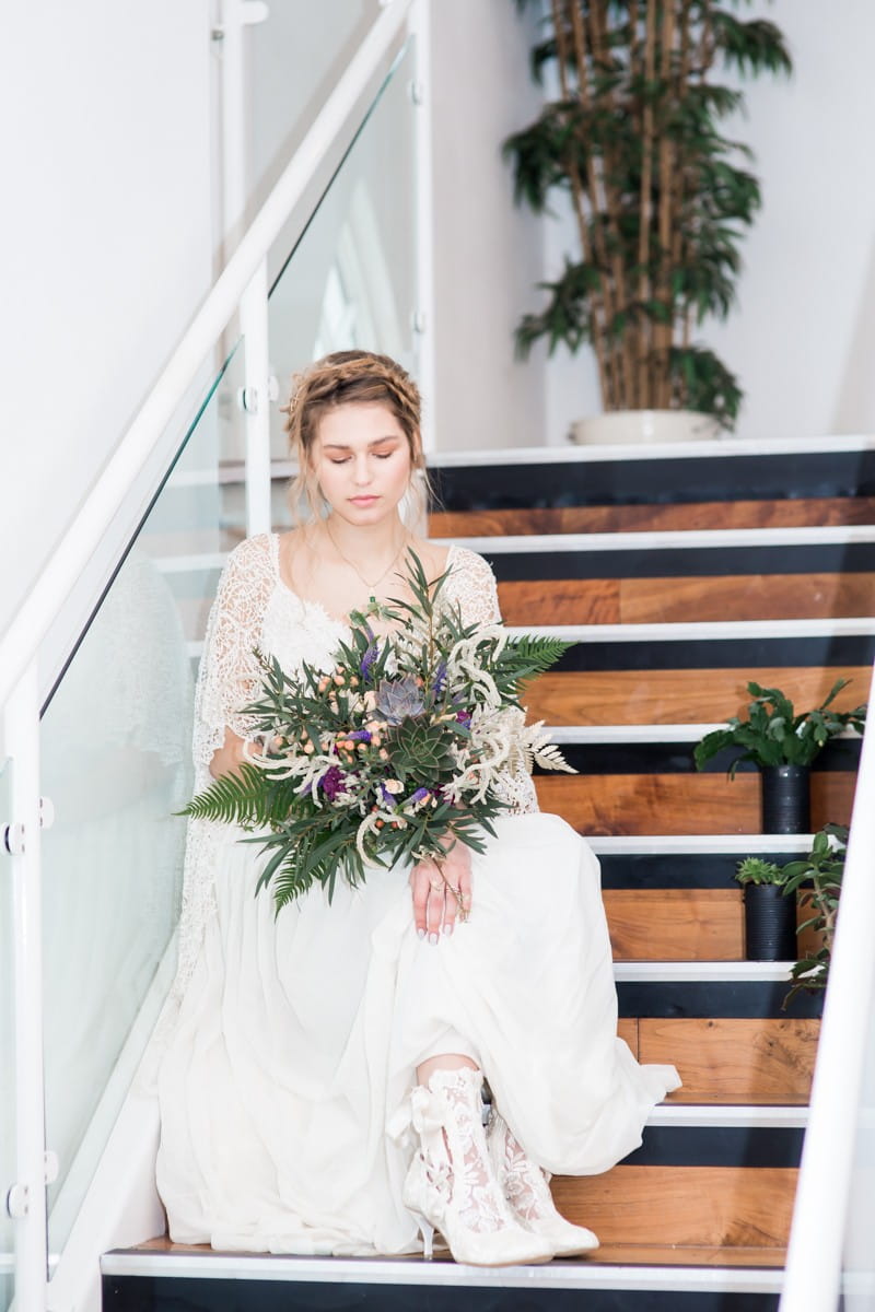 Bride sitting on steps holding bouquet