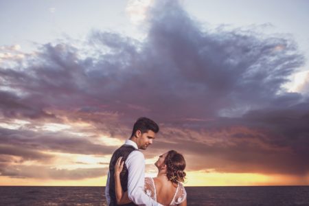 Bride and groom in front of clouds over the sea at sunset - Picture by AWPhotographic