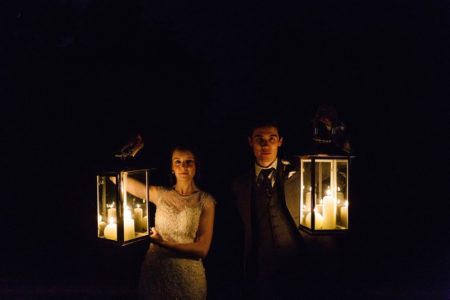 Bride and groom holding up candles in lanterns in the dark - Picture by Paul Joseph Photography