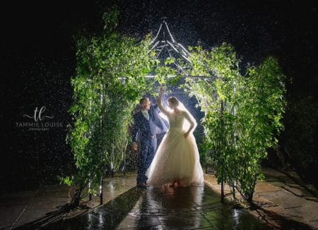 Bride and groom under foliage covered gazebo in rain at night - Picture by Tammie Louise Photography