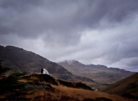Bride and groom on mountain near clouds - Picture by Story of Love