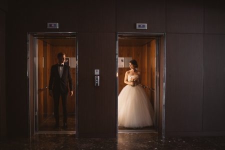 Bride and groom standing next to each other in separate lifts - Picture by Katja & Simon Photography