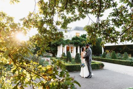 Picture of bride and groom in courtyard of wedding venue taken through tree branches - Picture by Fiona Kelly Photography