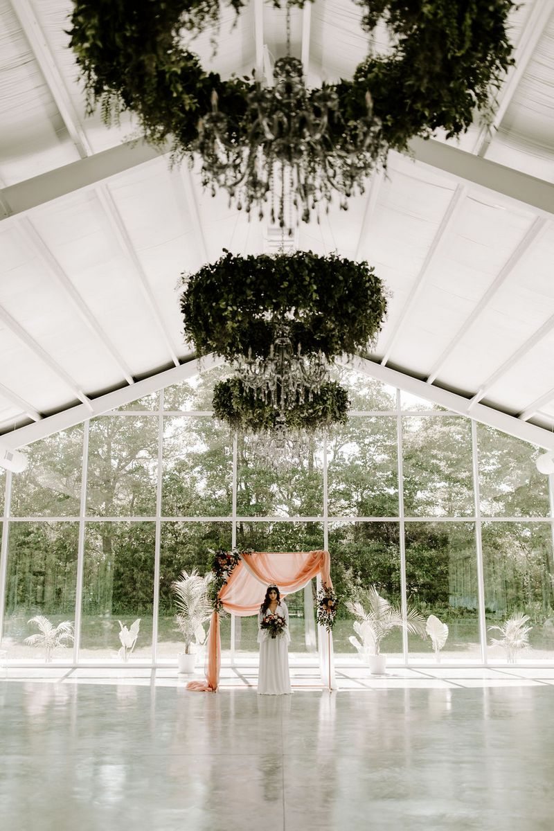 Bride standing in front of backdrop with hanging foliage installations overhead