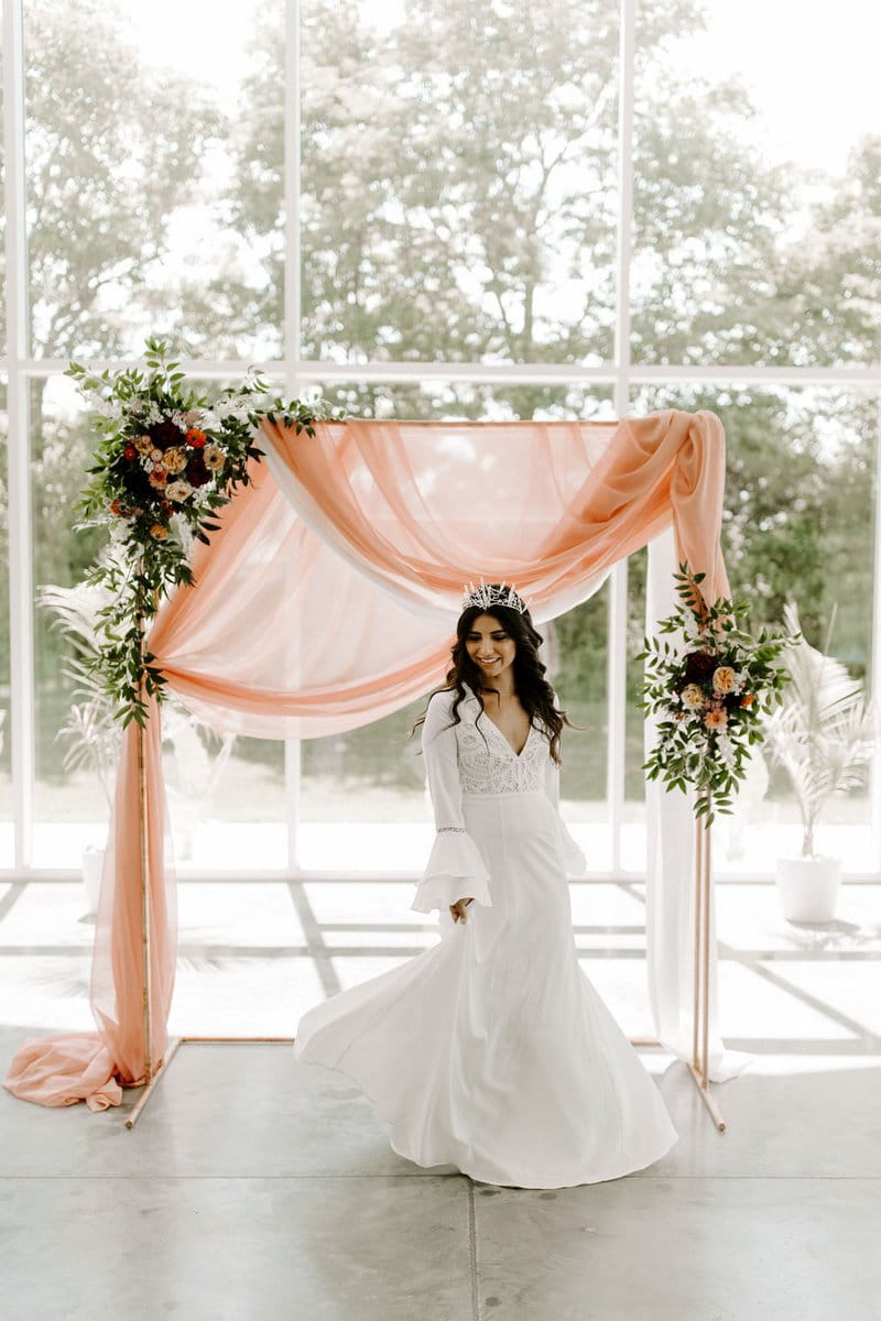 Bride standing in front of pink fabric ceremony backdrop