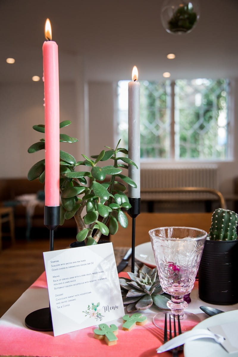 Pink and grey candles on wedding table with cactus plants