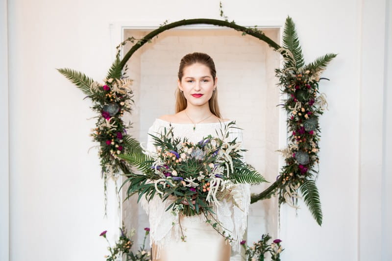 Bride holding bouquet in front of floral hoop