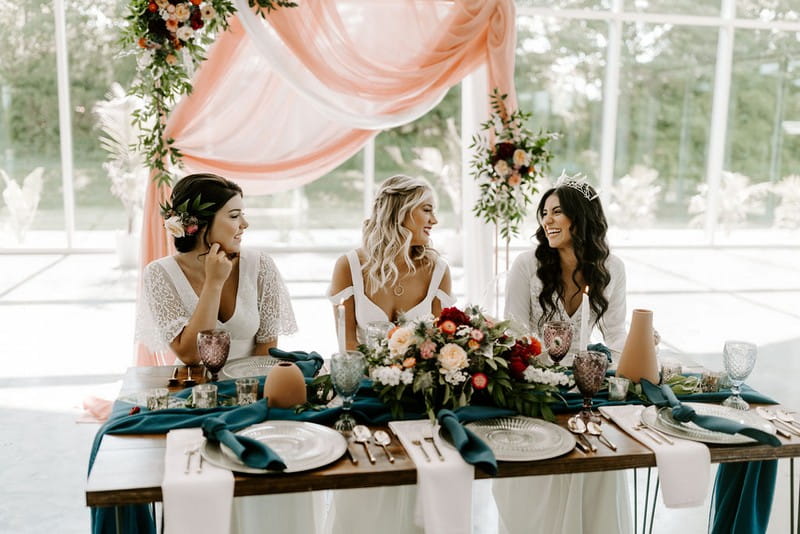 Three brides sitting at winter wedding table