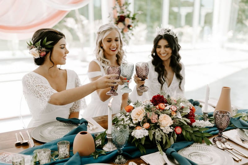 Three brides toasting at wedding table