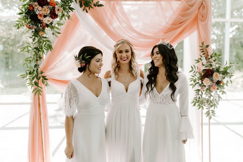 Three brides in front of pink fabric backdrop
