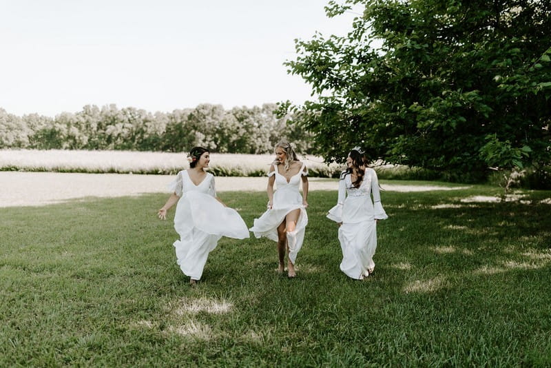 Three brides walking across grass at Greenhouse Two Rivers