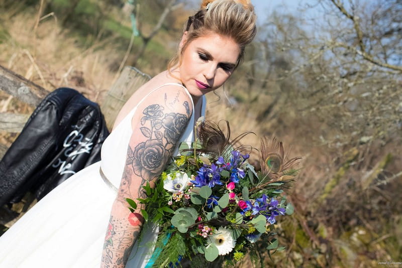 Bride with tattoos on arm holding bouquet