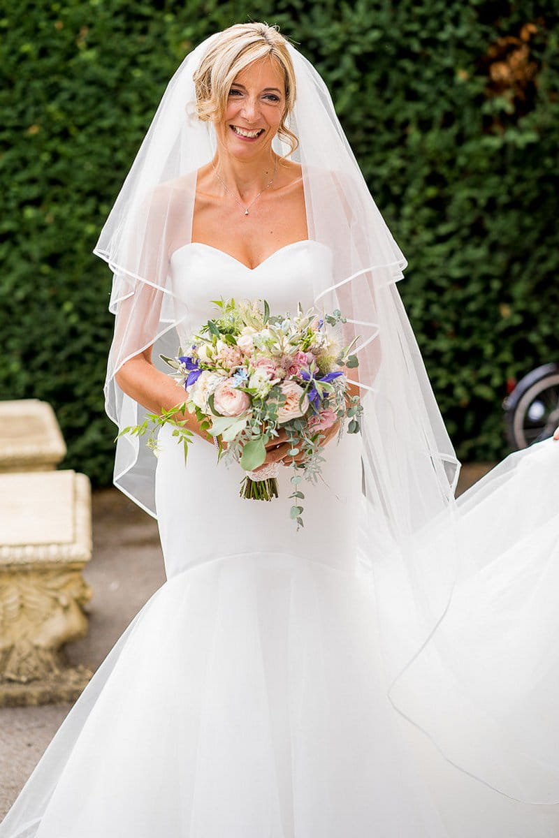 Bride smiling holding bouquet of garden flowers