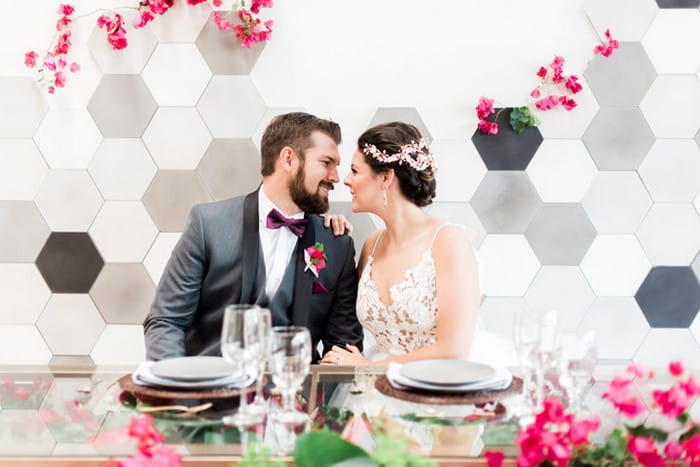 Bride and groom at wedding table in front of hexagonal backdrop