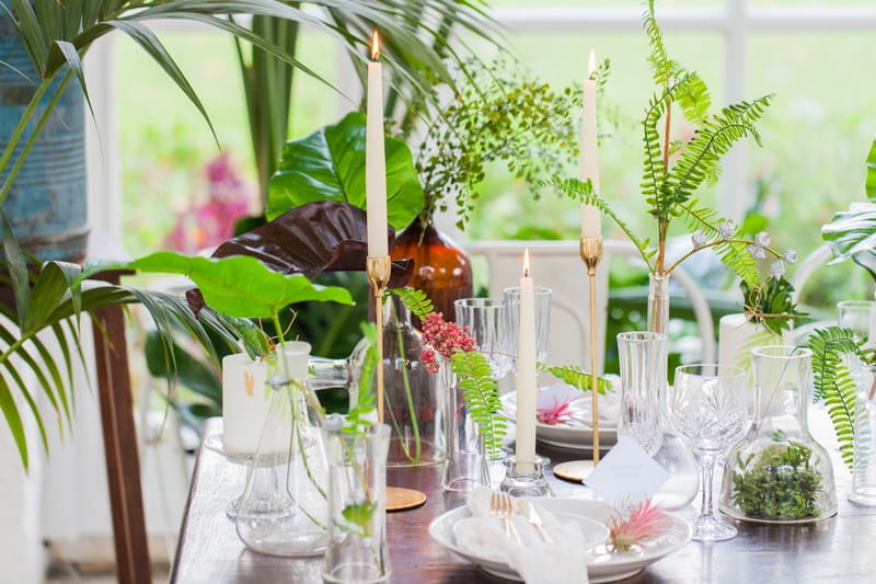 Wedding table styled with tropical leaves, white details and gold candlesticks