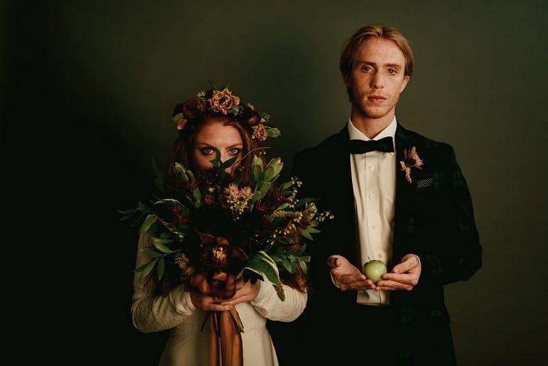 Bride holding bouquet to face as groom holds apple