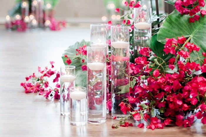 Vases of floating candles with pink bougainvillea and tropical leaves