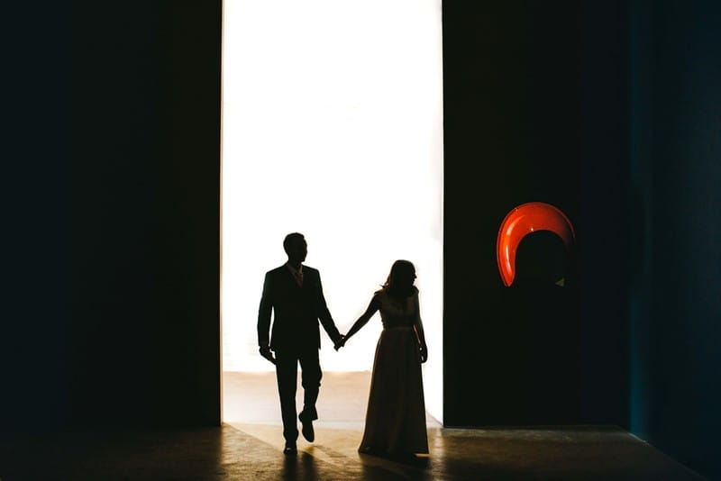 Bride and groom walking through bright doorway into dark room - Picture by Craig Williams Photography