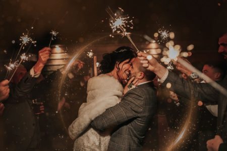 Bride and groom about to kiss surrounded by wedding guests with sparklers - Picture by The Soulcase
